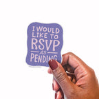 Hand holding a purple vinyl sticker with 'I would like to RSVP as pending' text on a white background