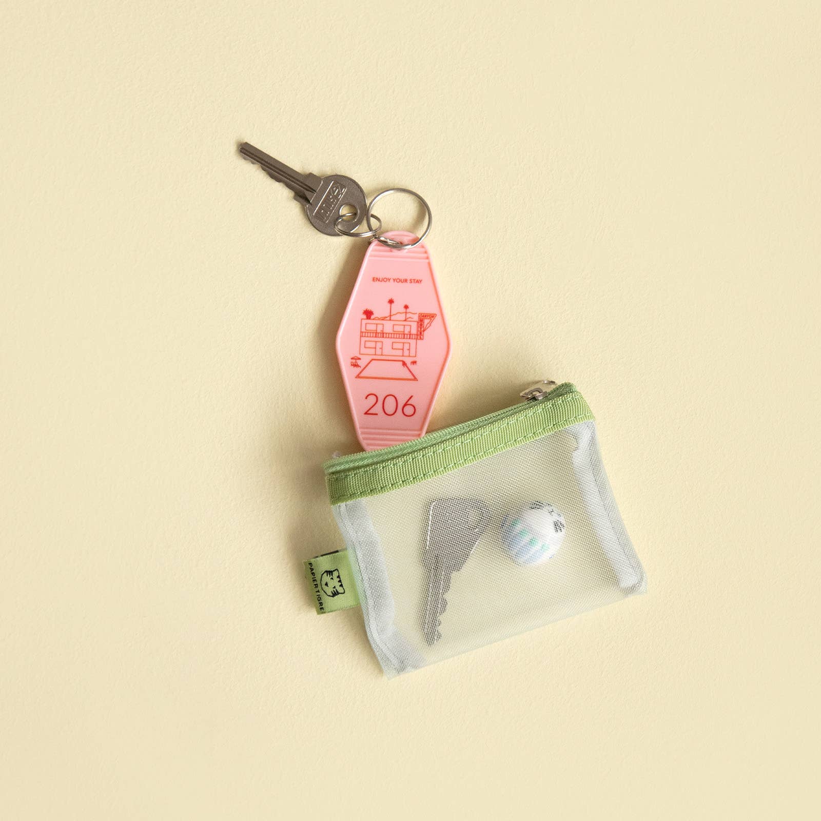 Green mesh pouch with keys in on a beige background