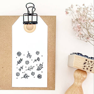 Floral stamp on a white background with a wooden handle and a small plant.
