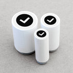 Three cylindrical white stamps with black check marks on a gray background
