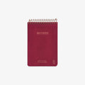 Red notebook with spiral binding on a white background
