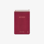 Red notebook with spiral binding on a white background