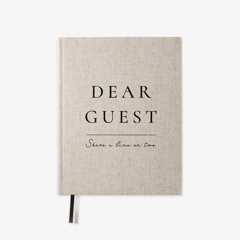 A linen-textured hardcover notebook with black printed text reading 'DEAR GUEST' and 'Share a line or two' on a clean white background.