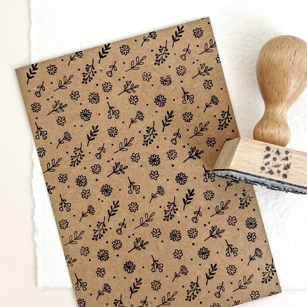 Kraft paper with black floral pattern and wooden stamp on a white background