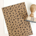 Kraft paper with black floral pattern and wooden stamp on a white background