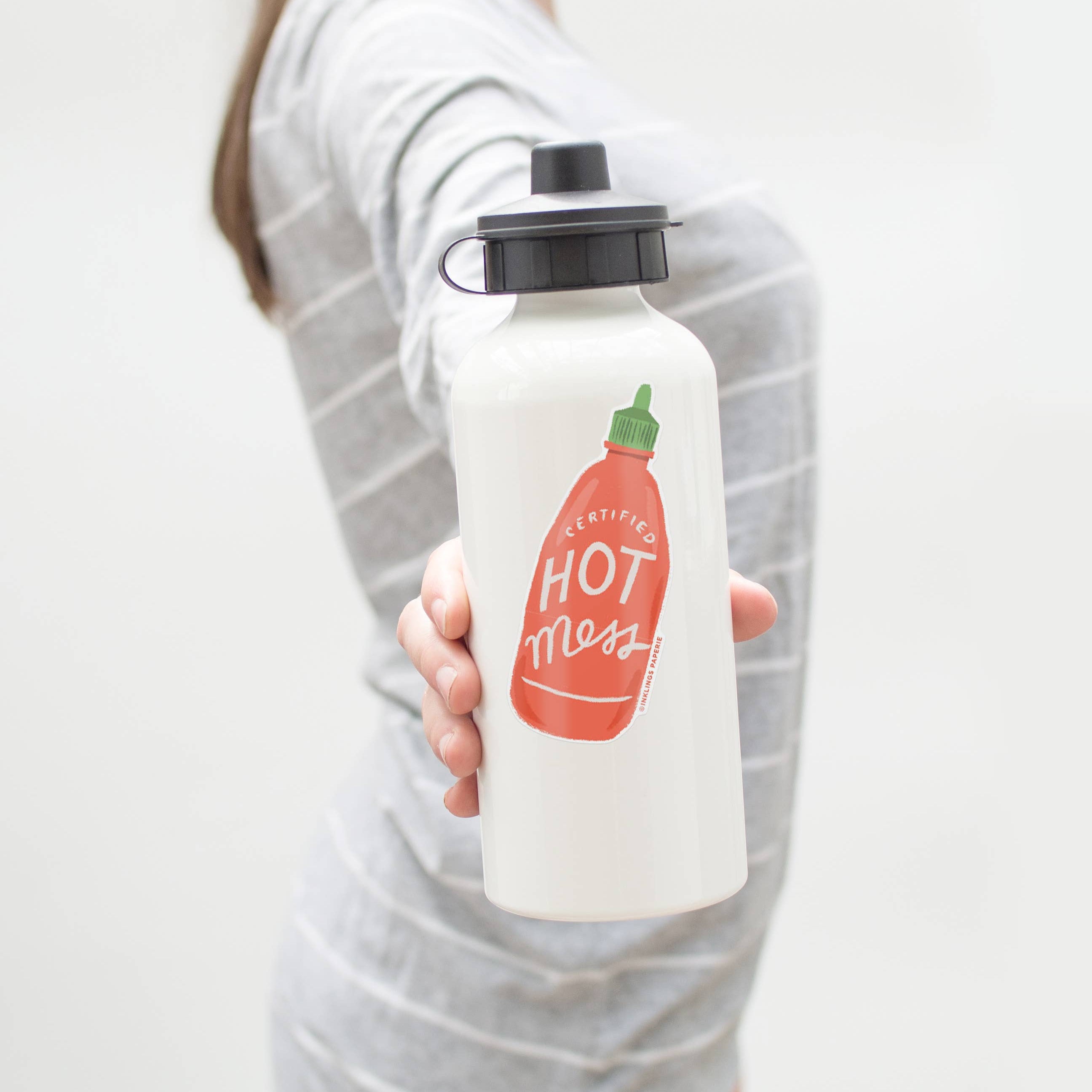 Person holding a white water bottle with a red and green vinyl sticker design on a plain background