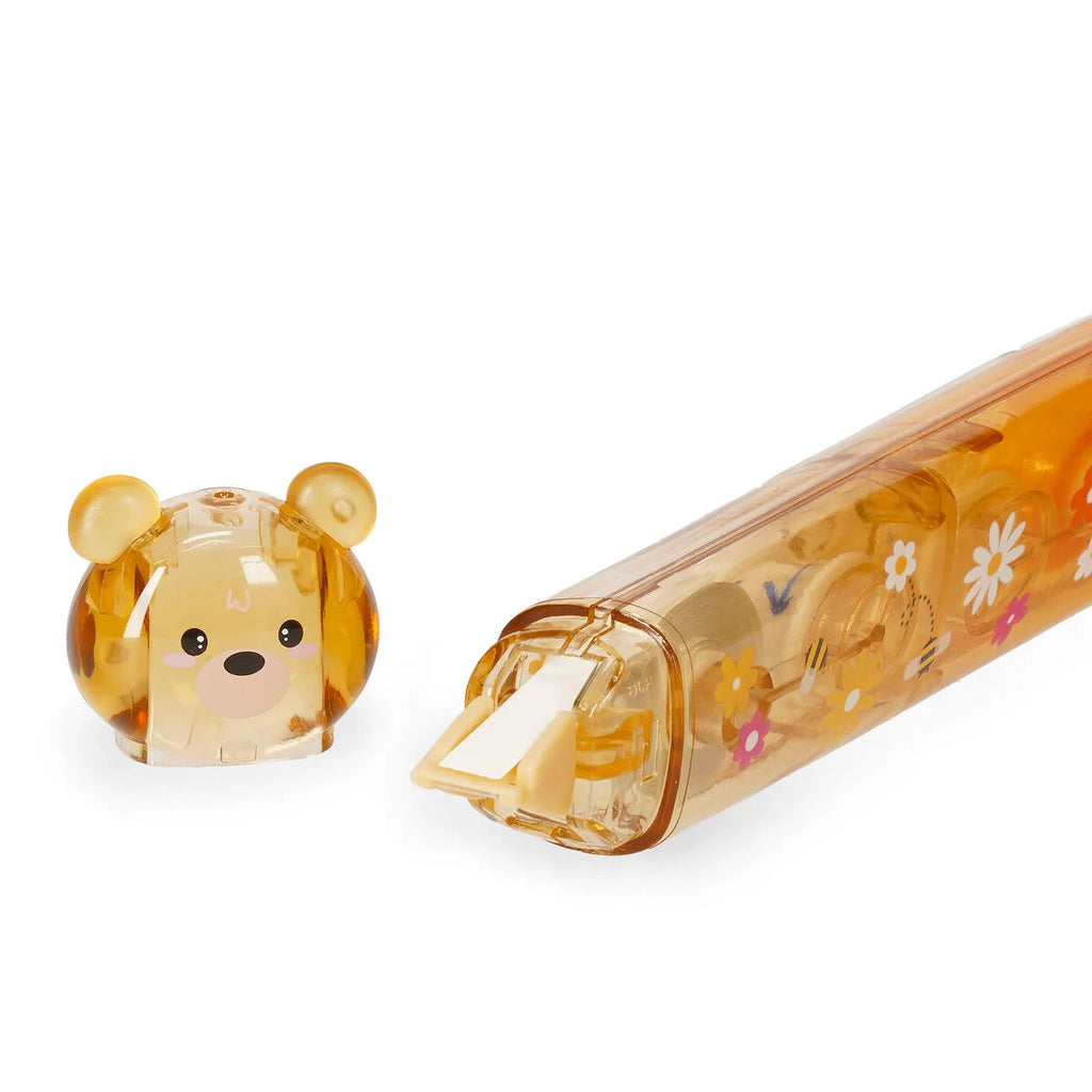 Transparent brownish correction tape pen with bear-shaped cap on a white background