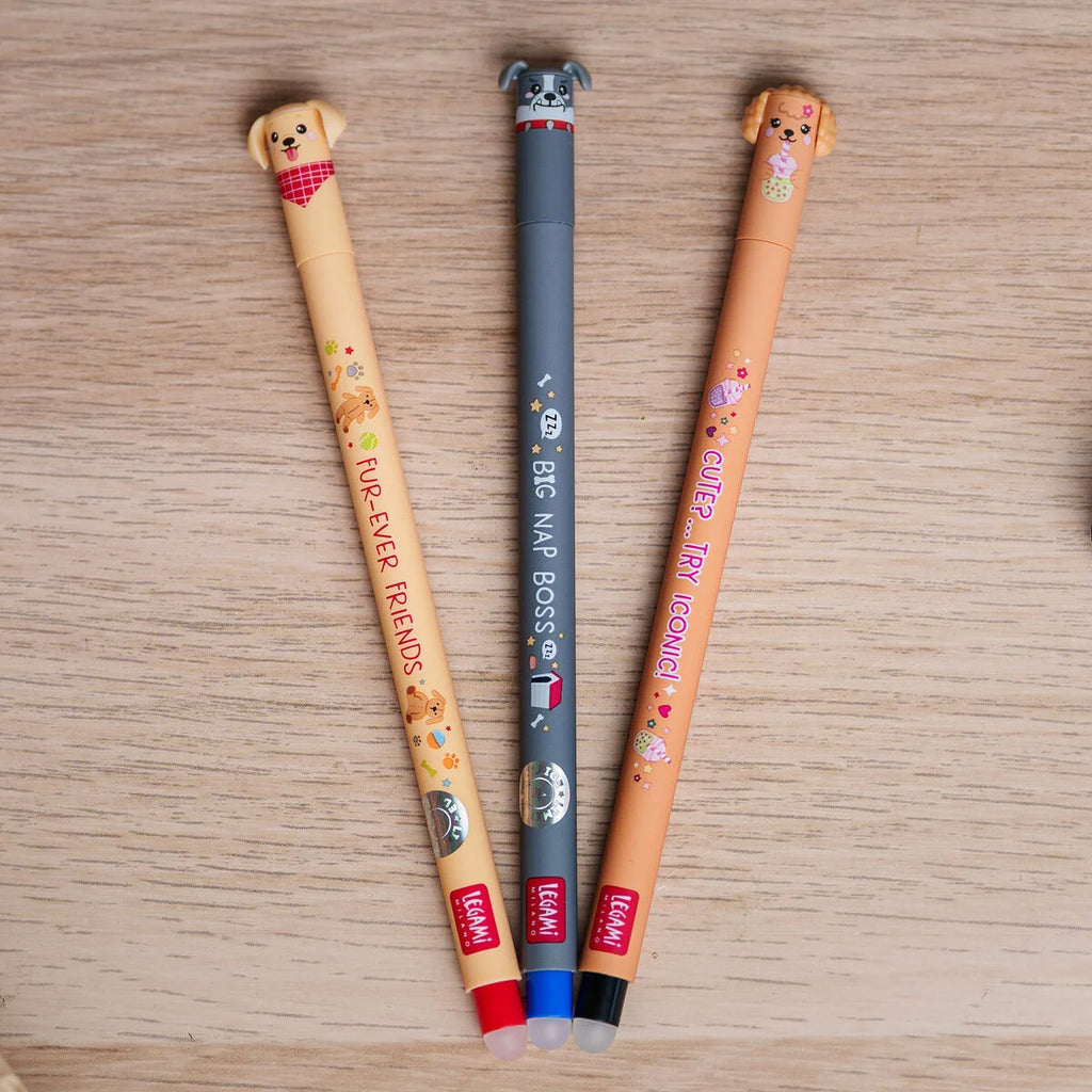 Three erasable gel pens with dog-themed designs on a wooden surface