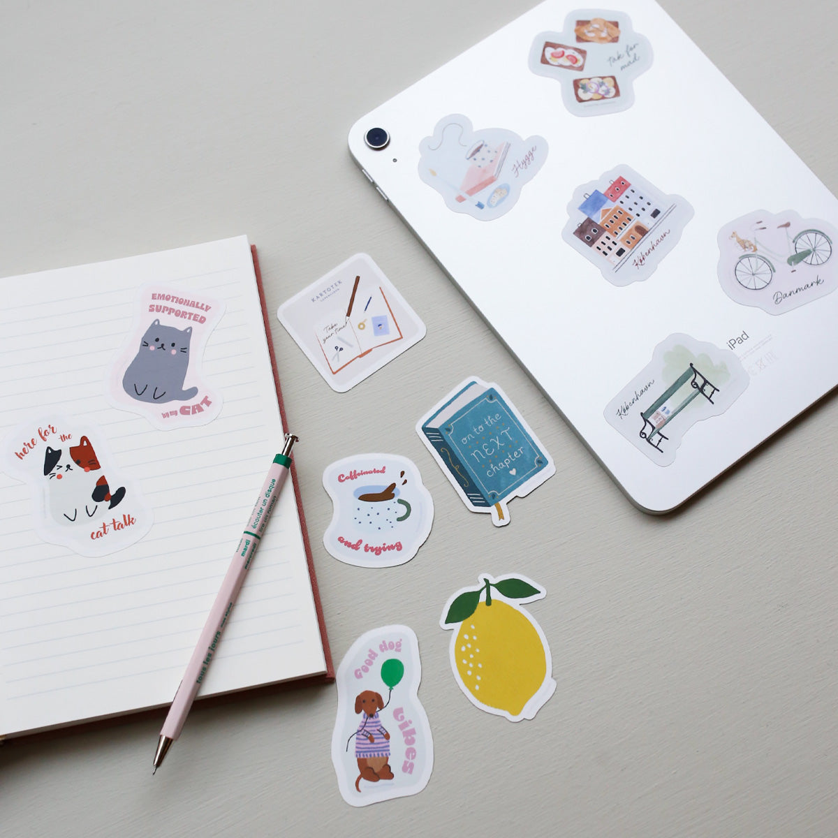 Decorative vinyl stickers on a notebook and tablet with a pen on a light gray background