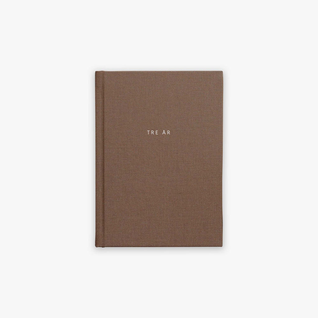 Brown guided journal with 'TRE ÅR' text embossed on the cover on a white background