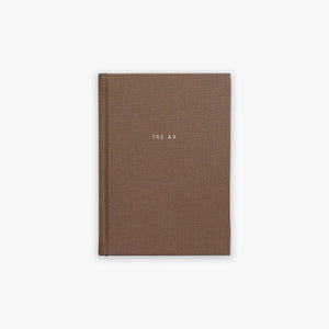 Brown guided journal with 'TRE ÅR' text embossed on the cover on a white background