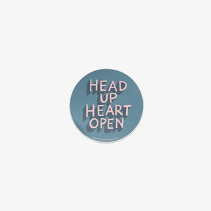 Round vinyl sticker with 'Head Up Heart Open' text on a light blue background