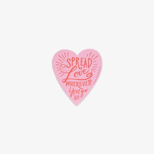 Pink heart-shaped vinyl sticker with 'Spread Love Wherever You Go' text on a white background