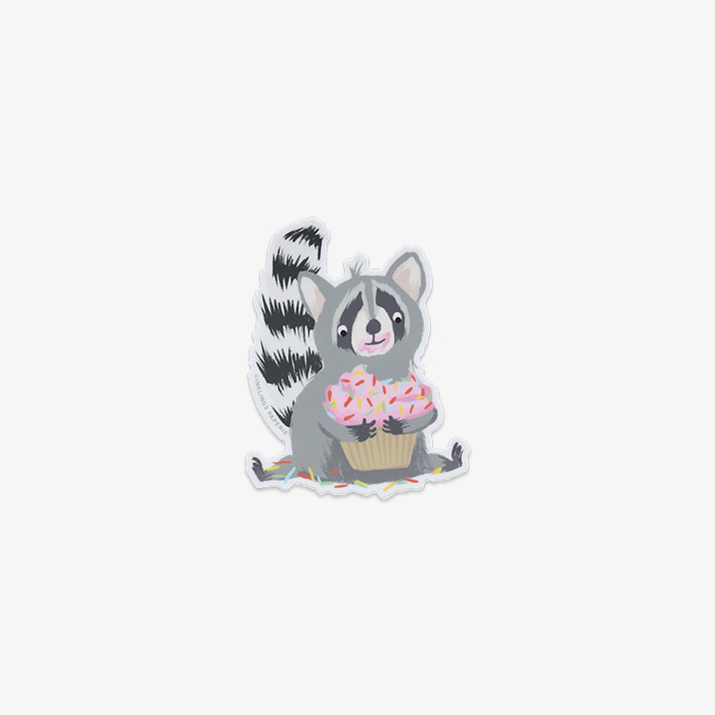 Vinyl sticker of a raccoon holding a cupcake on a white background