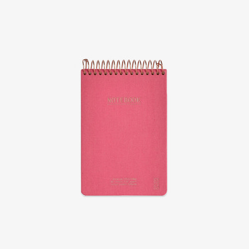 Pink notebook with gold spiral binding on a white background