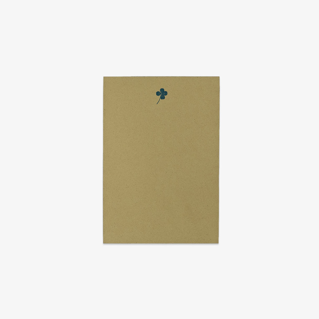 Green notepad with a dark green clover design on a white background