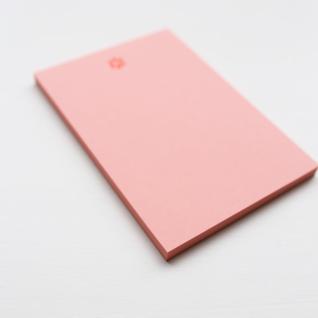 Pink notepad with paw print on a light gray background