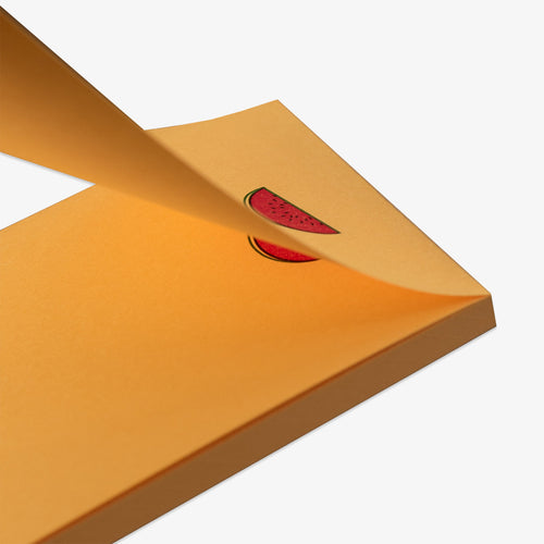 Close-up of a yellow notepad with a red watermelon sticker on a white background