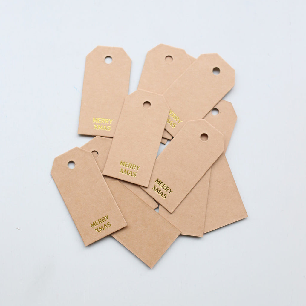 Kraft paper gift tags with 'Merry Xmas' text on a light gray background