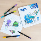 Milan colouring book with underwater-themed pages and coloured pencils on a wooden surface