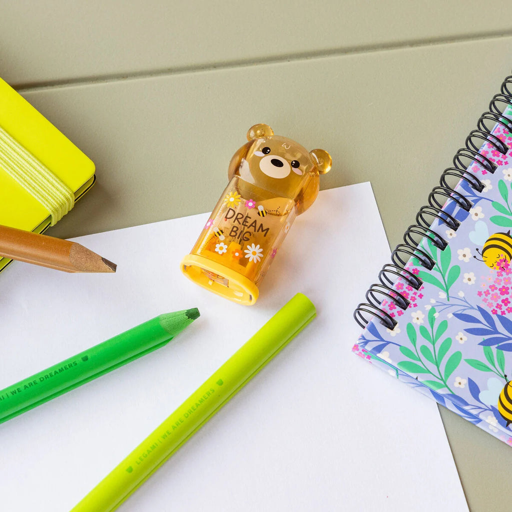 Bear-shaped pencil sharpener with 'Dream Big' text on a desk with pens and notebooks.