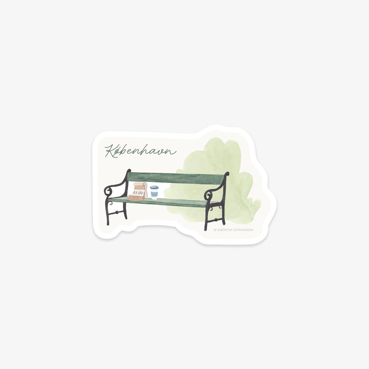 Vinyl sticker of a Copenhagen green bench with a bakery bag and to-go coffee on top and light green background and 'København' as text.