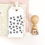 White card with black floral patterns and a wooden stamp on a light pink background