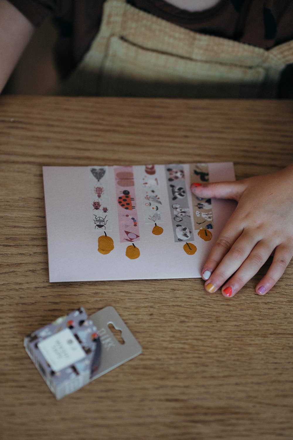 Hand holding a sheet of decorative washi tape on a wooden surface