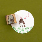 Wooden stamp with a bird design on a round white card with a printed design on a green background
